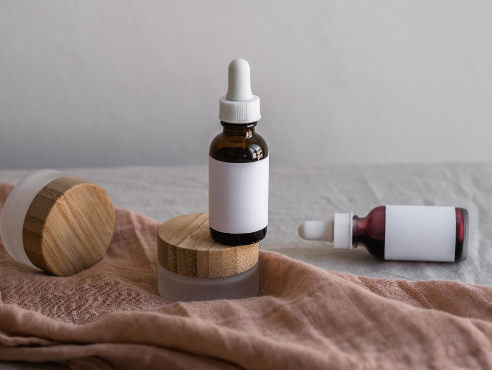 Amber glass dropper bottles with blank white labels resting on a soft linen surface.