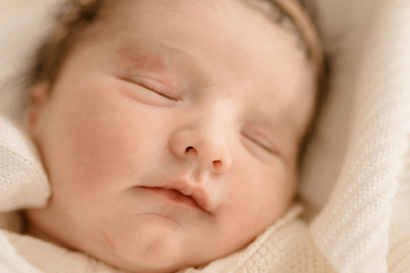 Close-up of a peacefully sleeping baby's face in warm light.