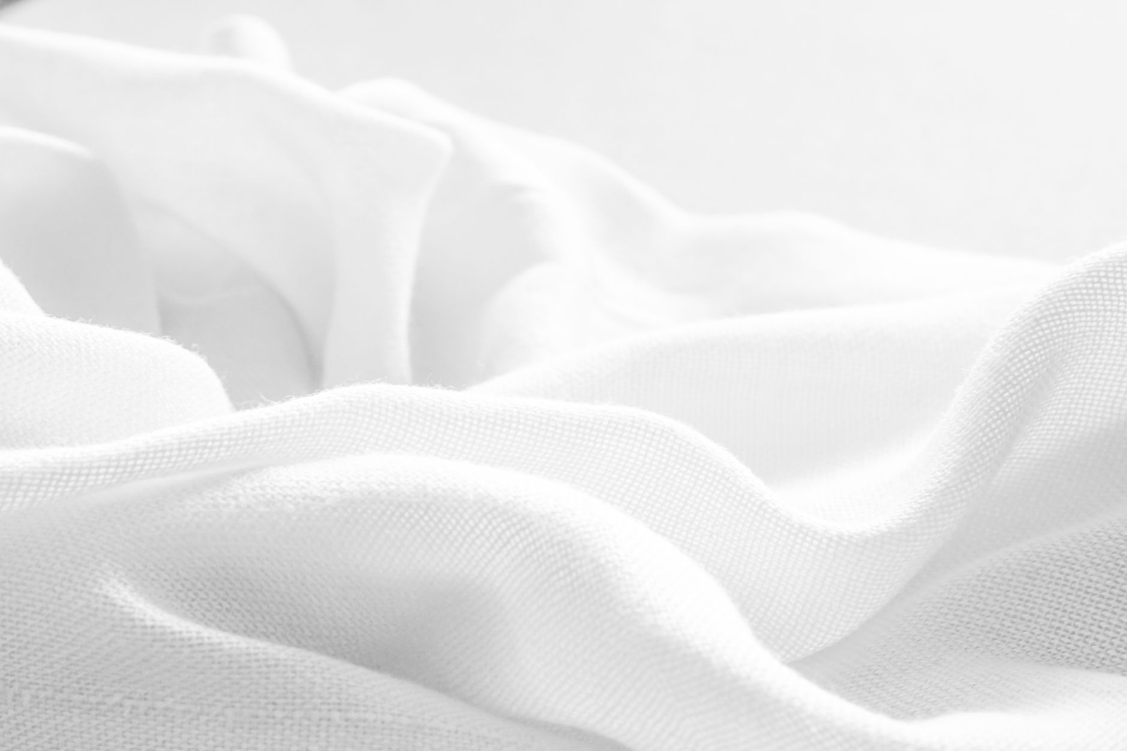 Soft, smooth white cotton fabric with gentle folds, evoking breathable comfort against skin.